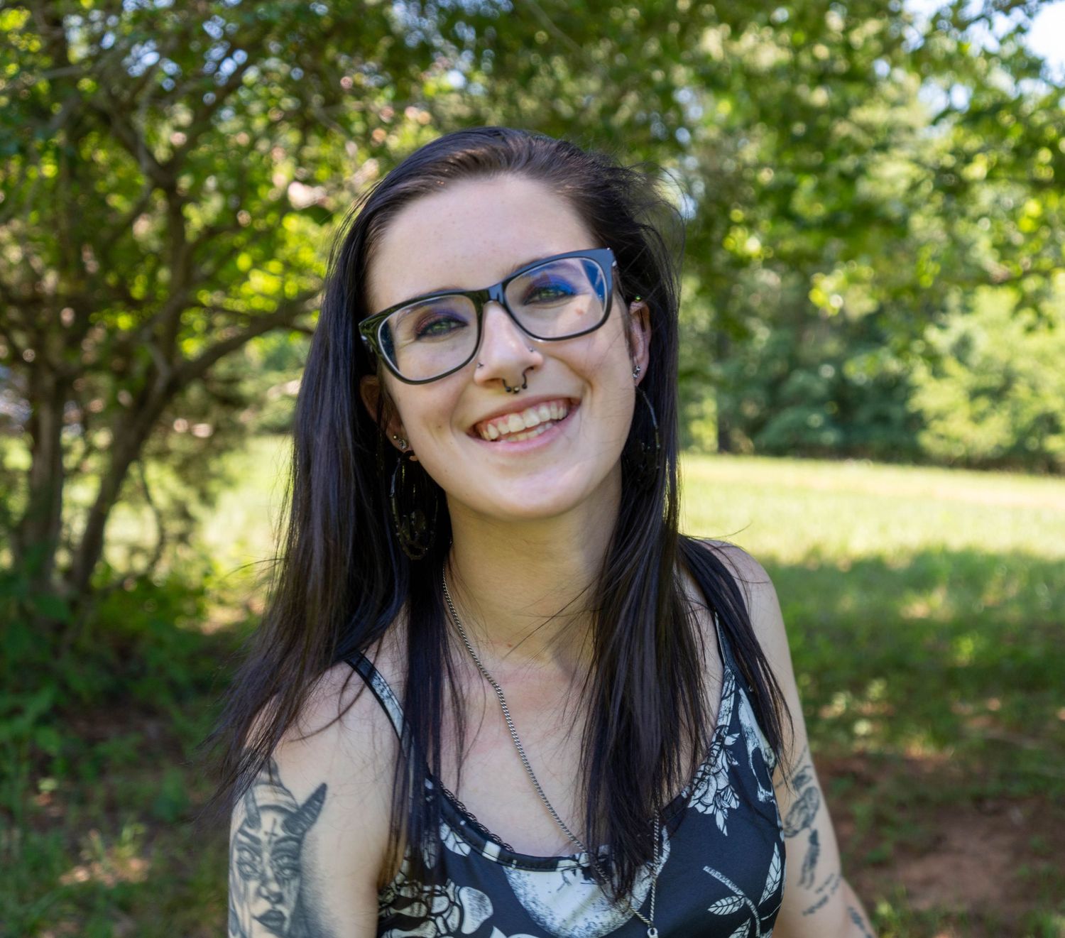 Close-up outdoor portrait of a smiling woman with glasses.