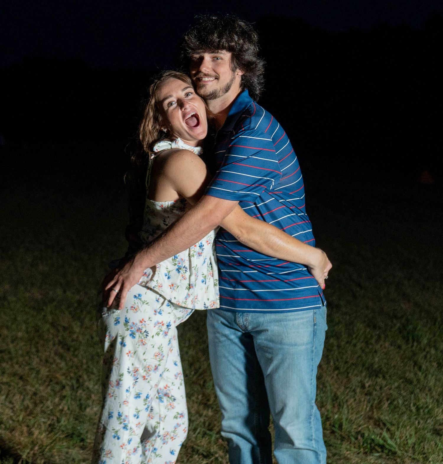 Couple embracing outdoors beneath fireworks at night