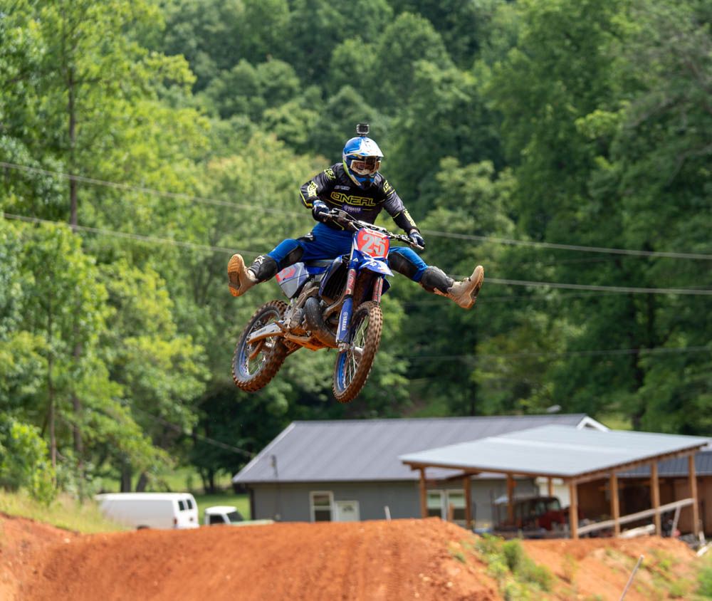 Motocross rider airborne over a jump with the bike turned sideways.