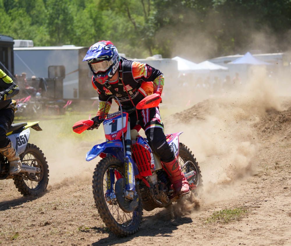Motocross rider leaning through a dusty turn during a race.