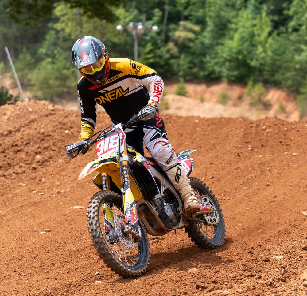 Motocross rider racing across a red dirt track.
