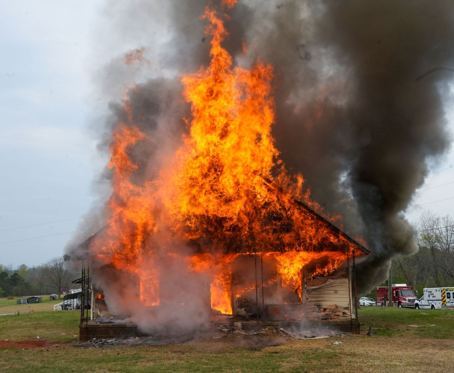 House fully engulfed in flames and heavy smoke during a firefighter training exercise.