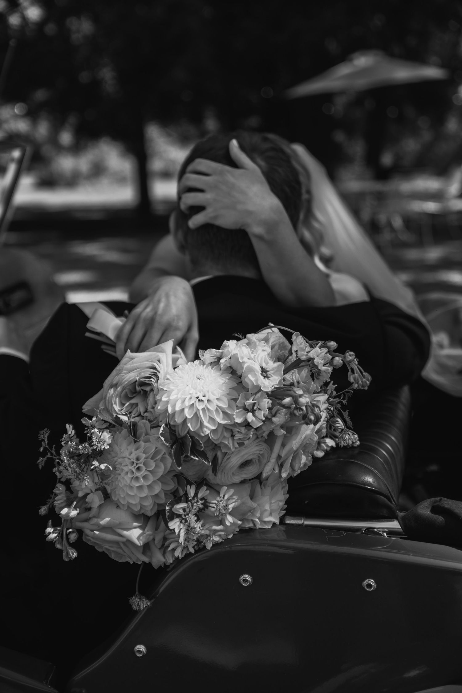Black and white image showing delicate floral headpieces adorning the backs of chairs at a formal event.