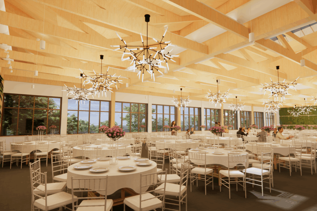 Elegant wedding reception hall with white tables, crystal chandeliers, and exposed wooden beams on the ceiling.