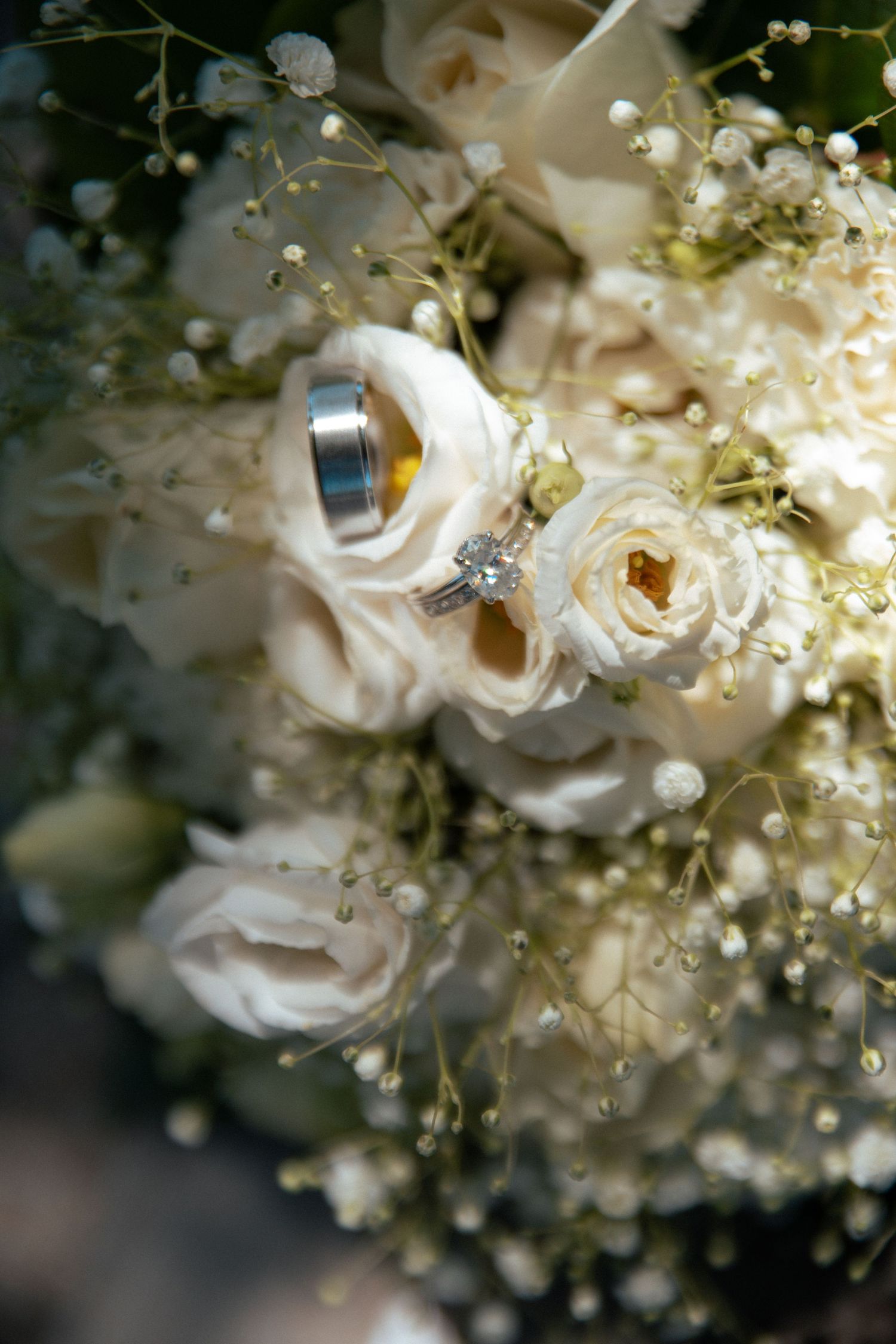 Wedding rings rest elegantly among white roses and baby's breath in a bridal bouquet.