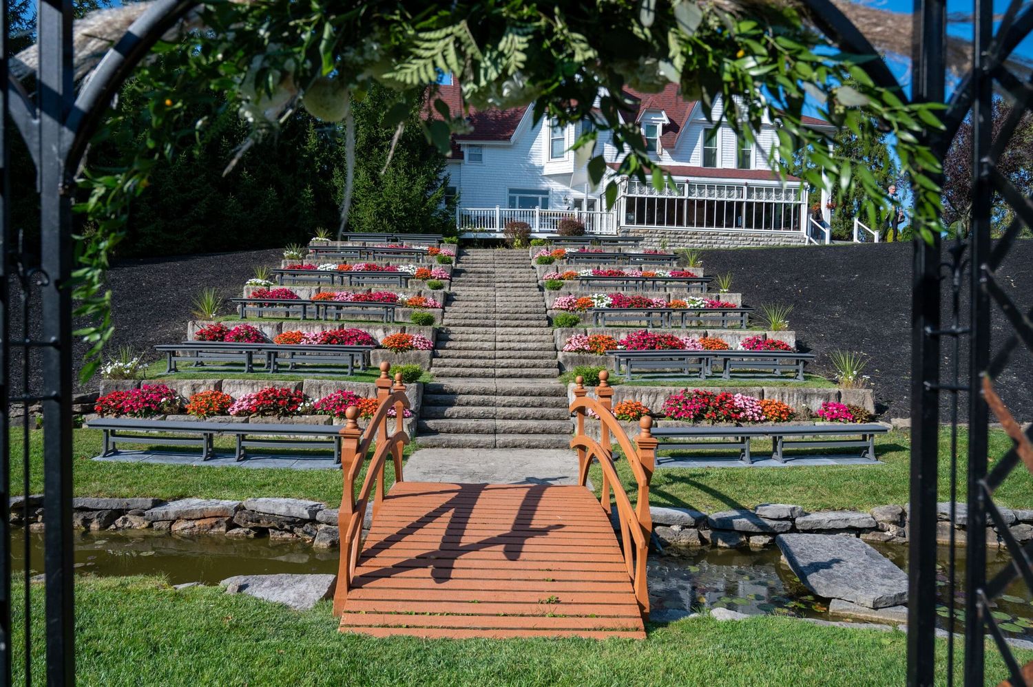 A series of wooden stairs with red handrails leads up a grassy slope in a public park setting.