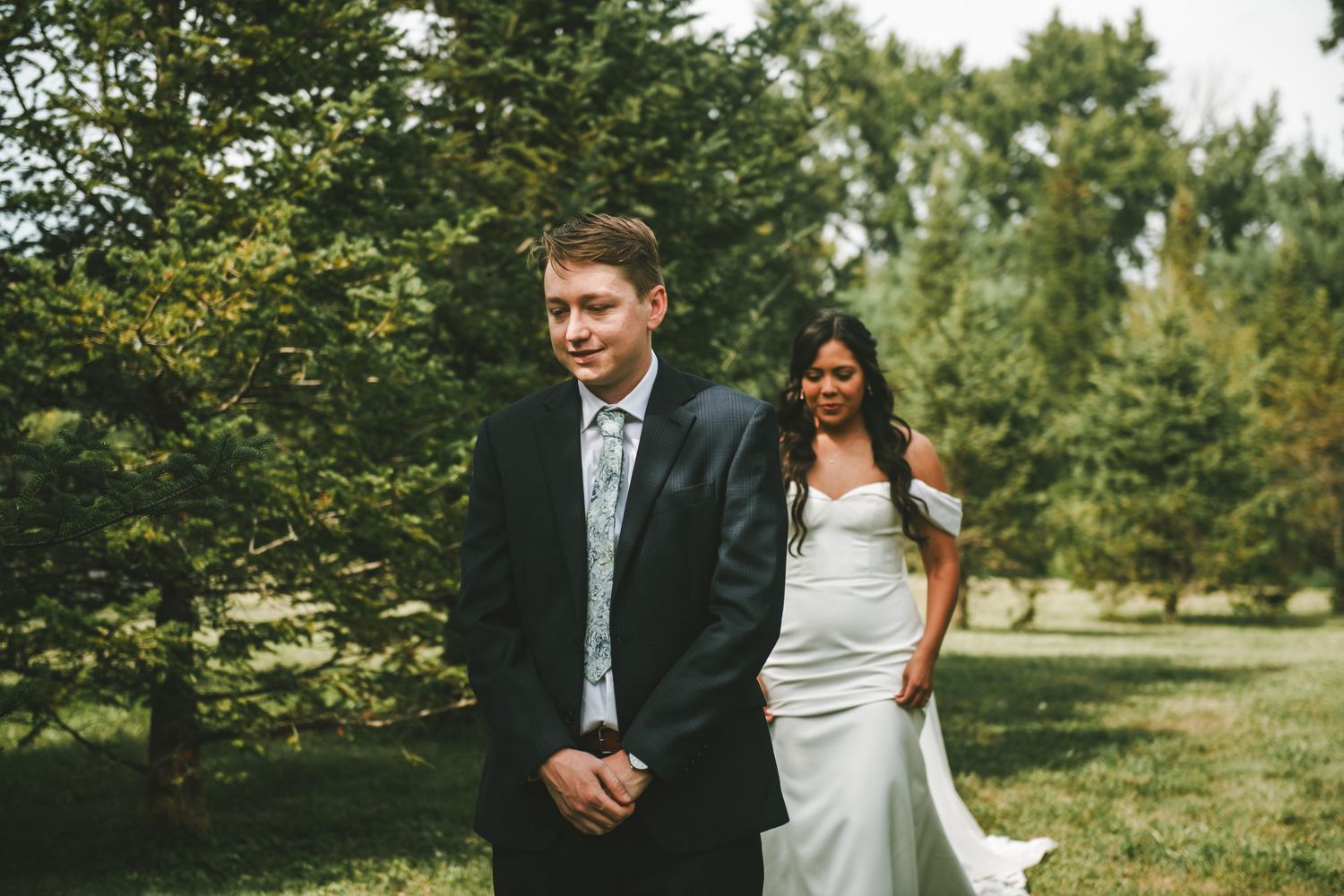 A couple in wedding attire walks together through a lush green garden setting on their special day.