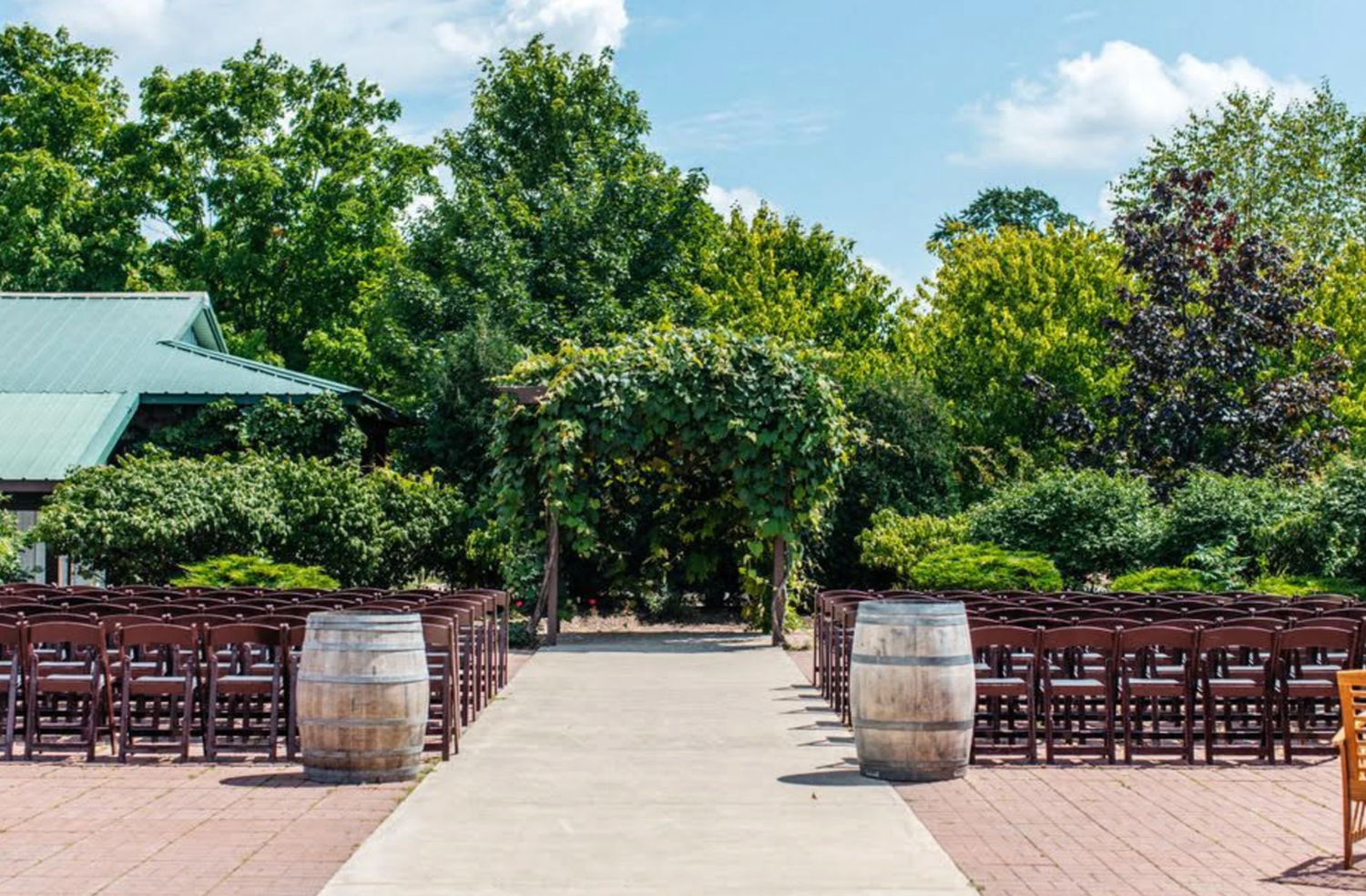 A panoramic view of an outdoor garden patio with rows of empty wooden chairs set up for an event or ceremony.