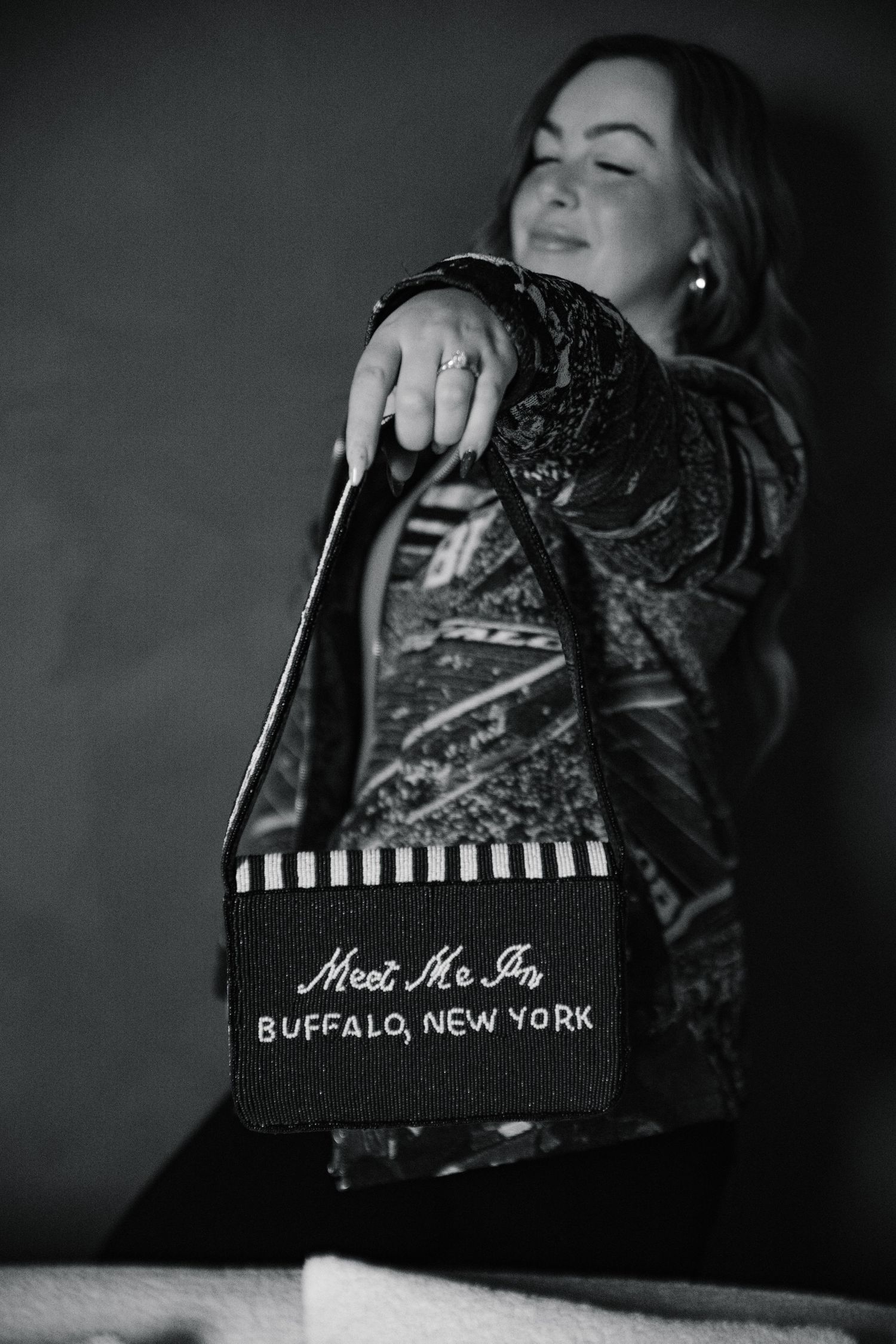 Black and white photo of woman holding a tote bag reading Meet Me In Buffalo, New York.