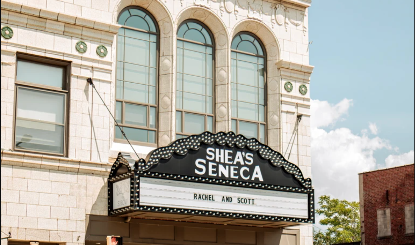 Vintage movie theater marquee and facade with ornate architectural details against a blue sky.