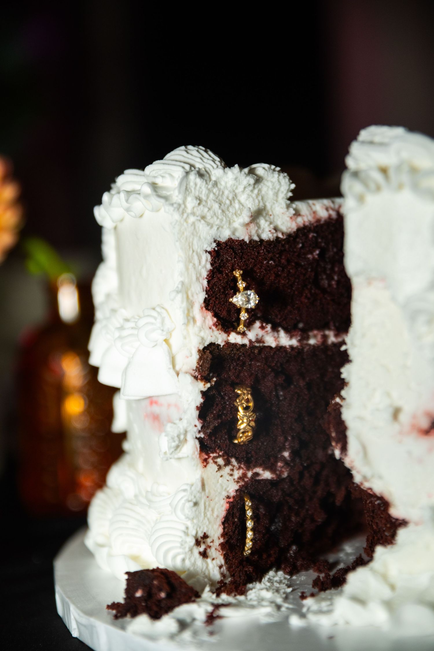 Sliced white frosted chocolate layer cake with gold decorations and cream piping on a white cake stand.