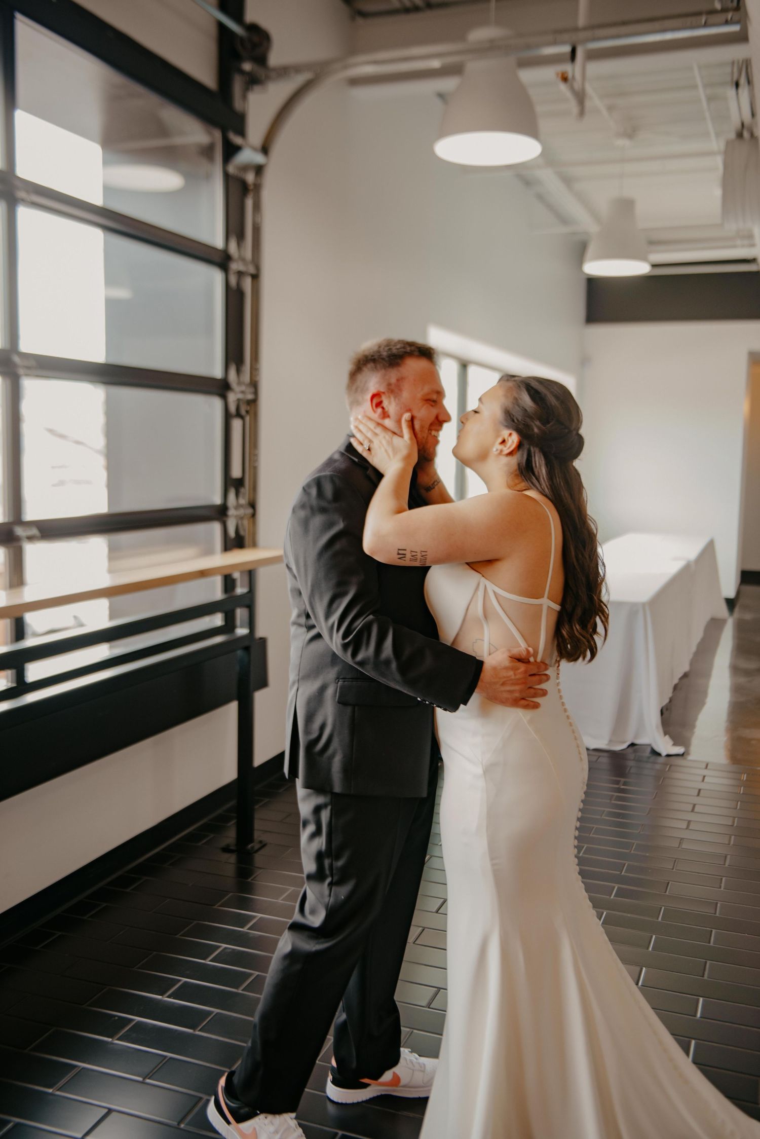 A couple shares an intimate dance together in a modern indoor space with black tile floors and white walls.