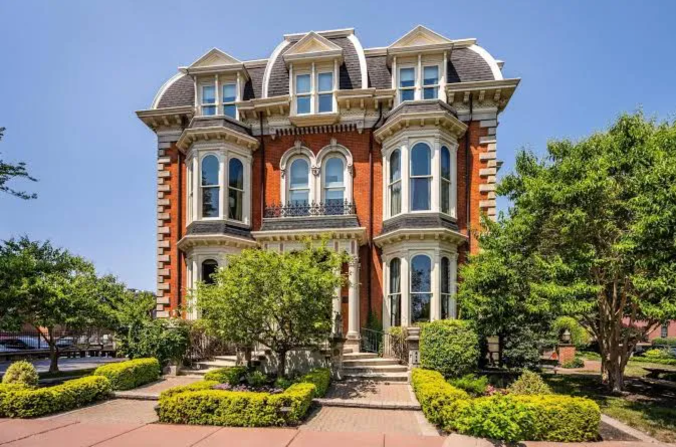 Elegant Victorian mansion with red brick exterior and ornate architectural details features multiple bay windows and dormers.