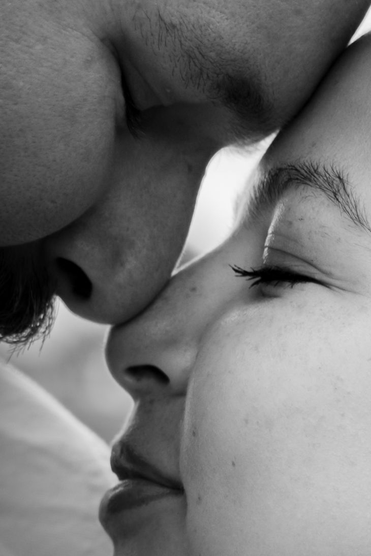 Black and white close-up of a romantic couple sharing an intimate moment, faces nearly touching with eyes closed.