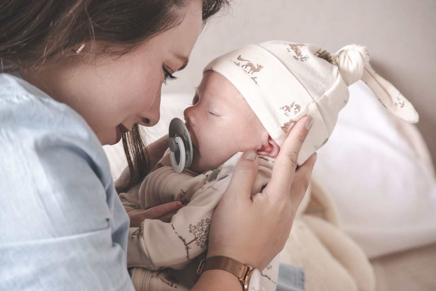 A tender moment as a young mother lovingly feeds her newborn baby wearing a cute animal print hat.