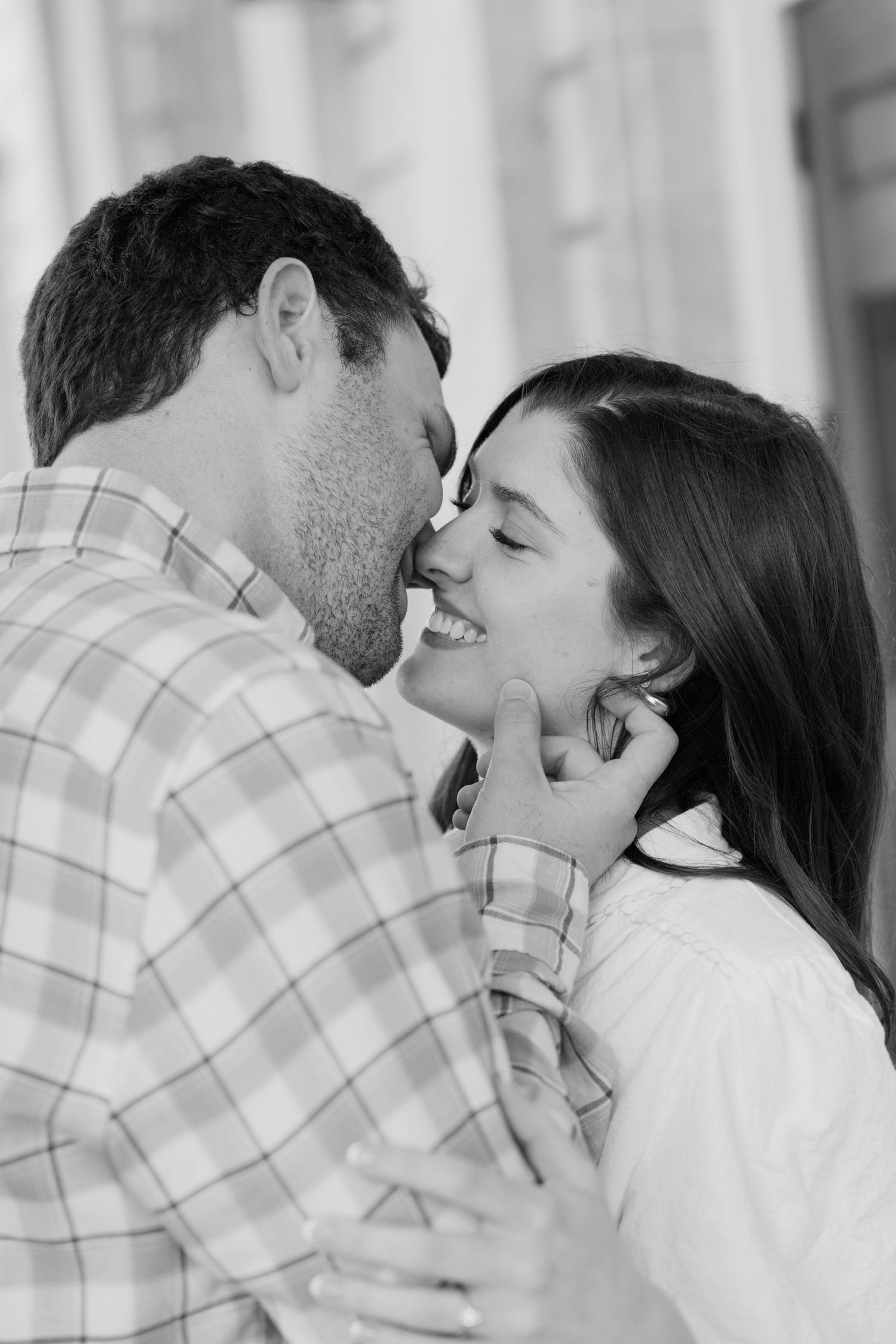 Black and white photo of a smiling couple sharing a tender moment, the man gently cupping the woman's face.