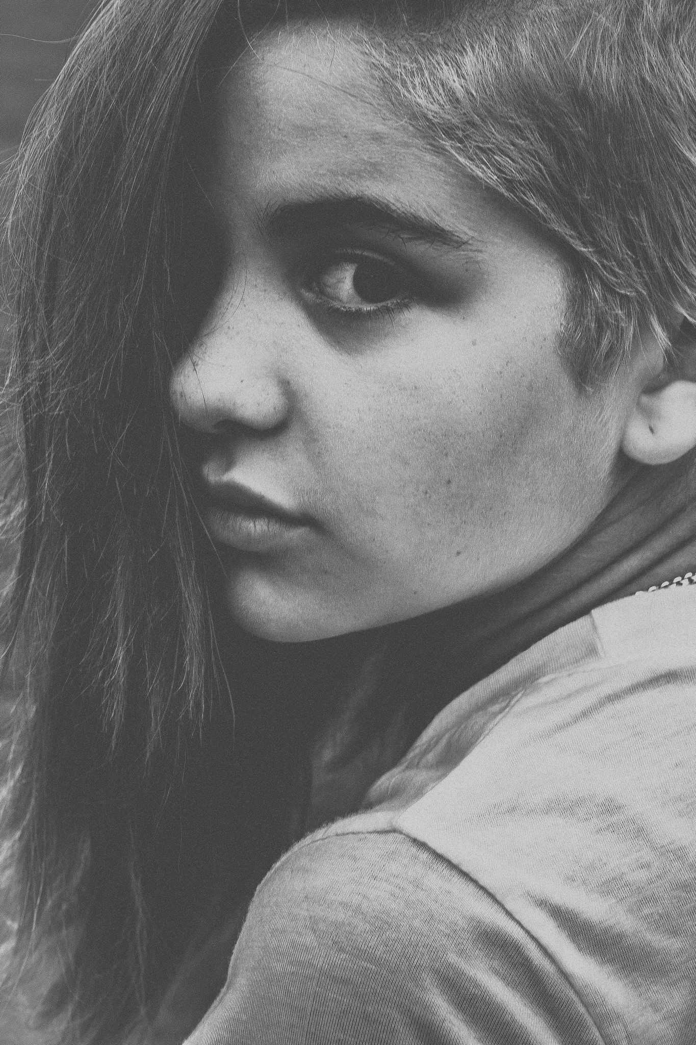 Black and white close-up portrait of a young woman with long hair gazing thoughtfully at the camera.
