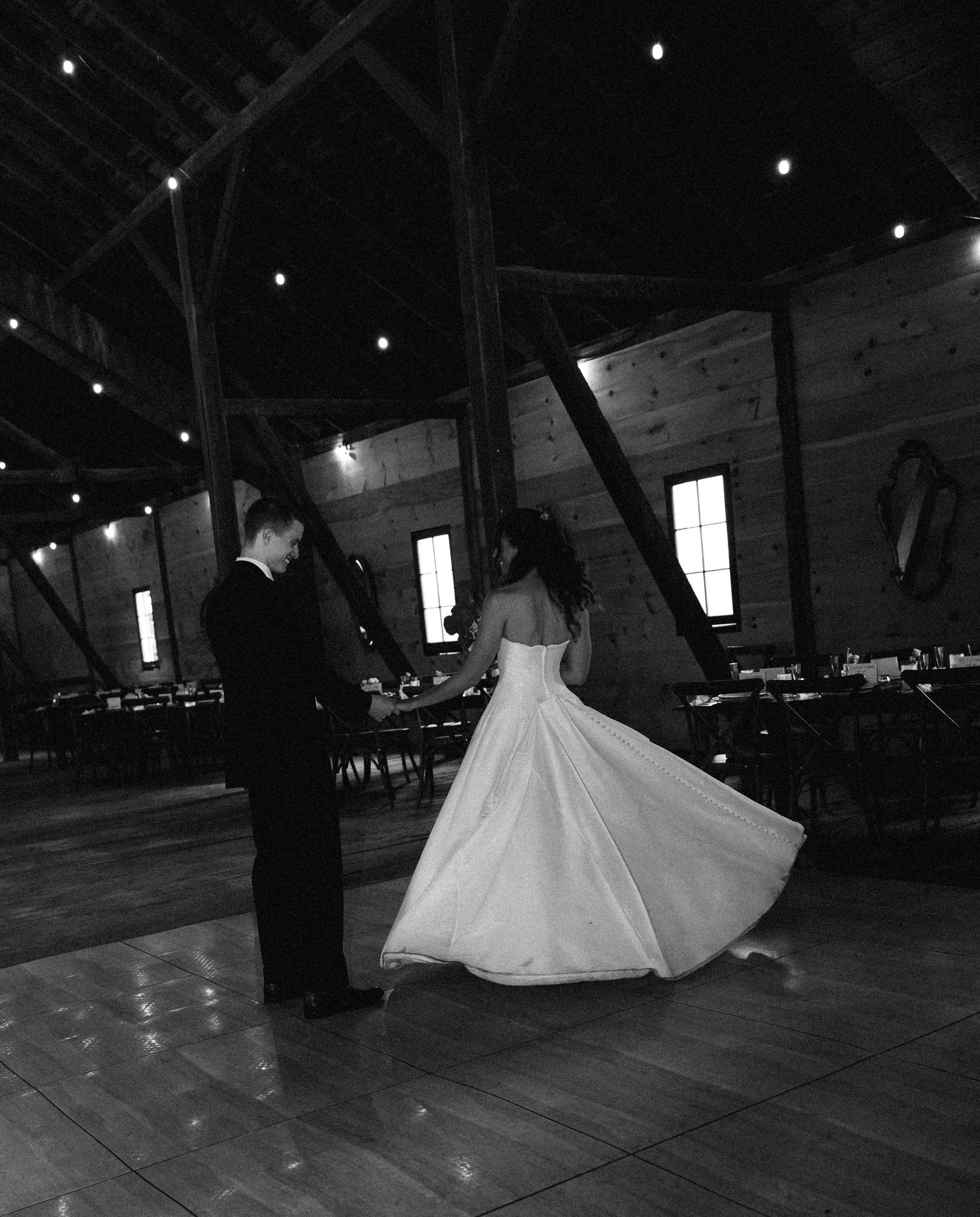 Black and white photo of bride and groom sharing their first dance in a romantic barn reception venue.