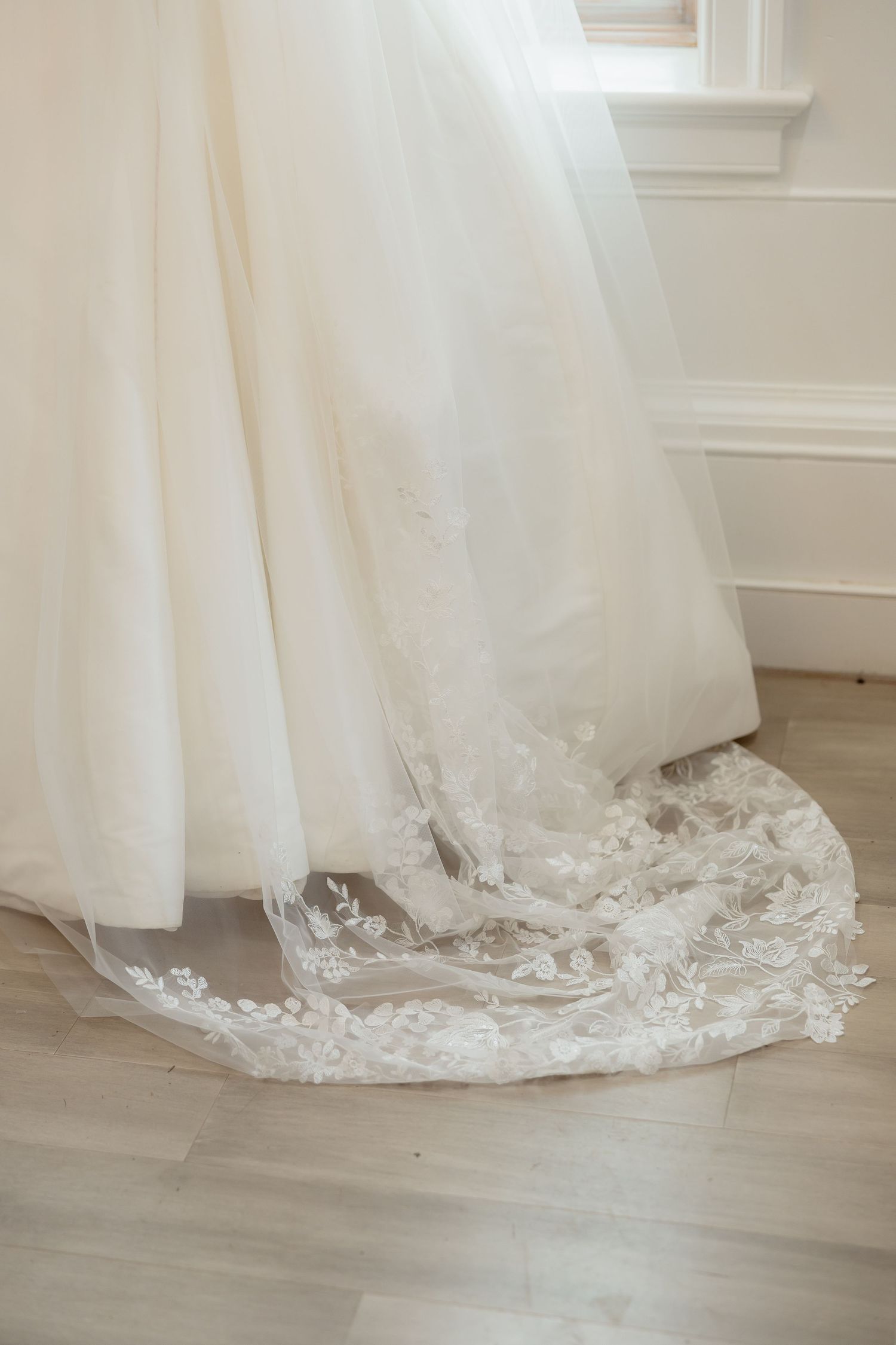 Close-up of delicate floral lace trim on the train of a white wedding gown.