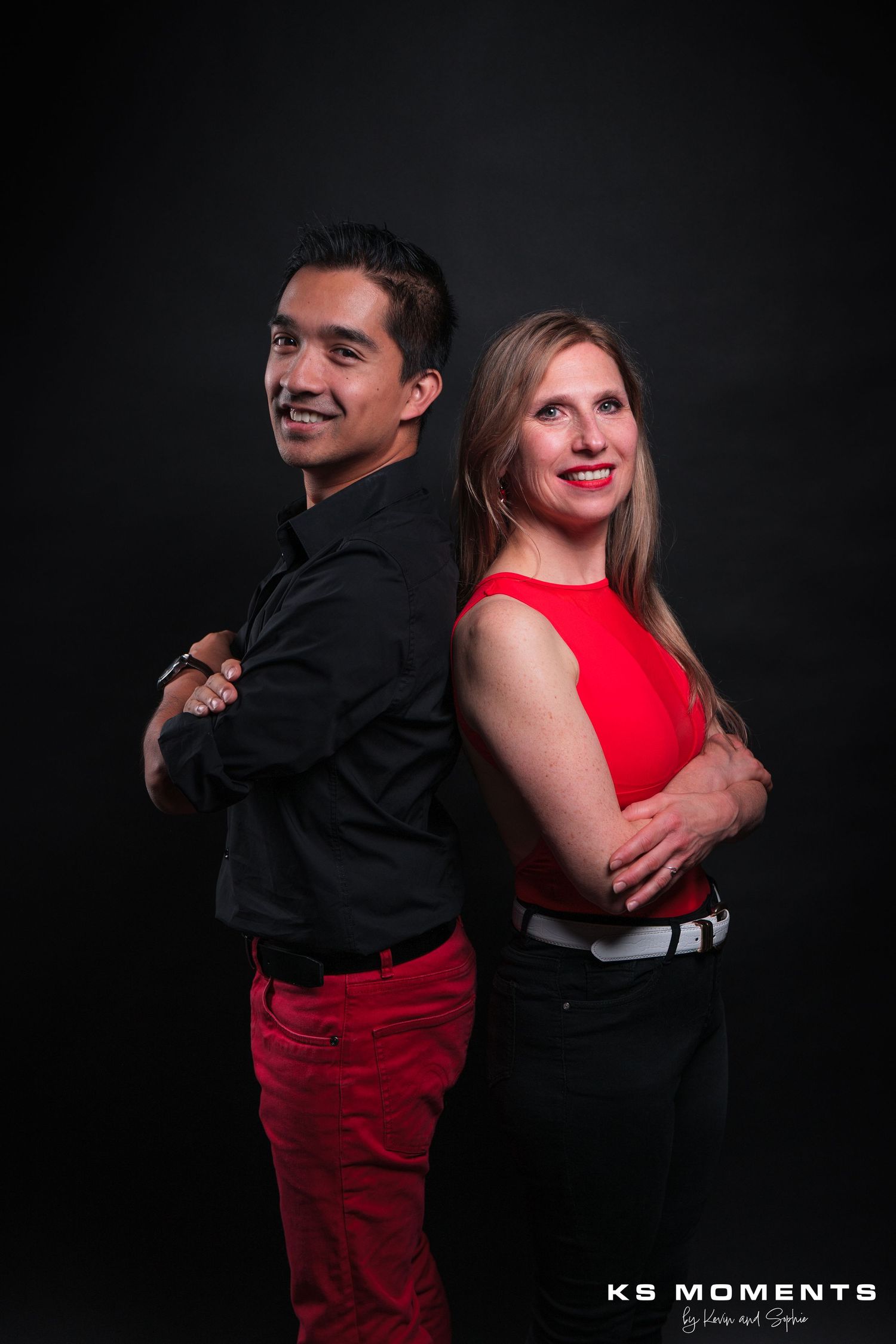 Photo d'un couple souriant dos à dos dans un studio photo avec un fond noir