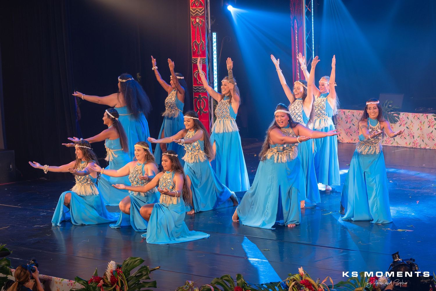 Photo d'un grand groupe de danseuses polynésiennes levant les bras en l'air sur une scène