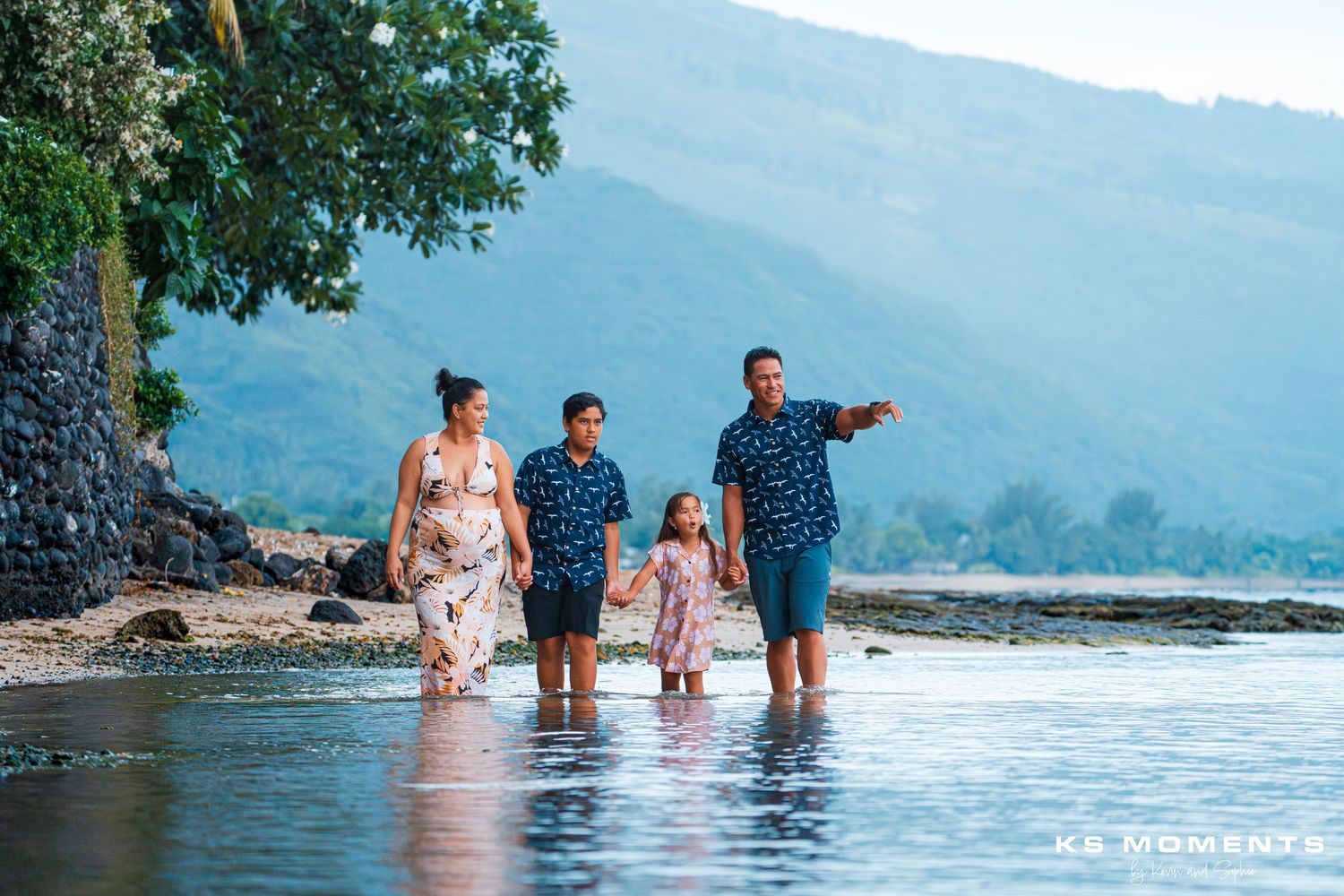Photo d'un famille de quatre personne regardant vers la droite dont le papa montre quelque chose au loin