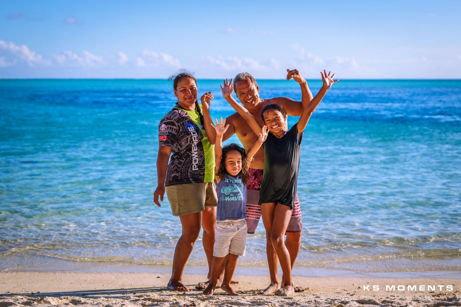 Photo d'une famille polynésienne sur une plage avec de l'eau turquoise en arrière plan