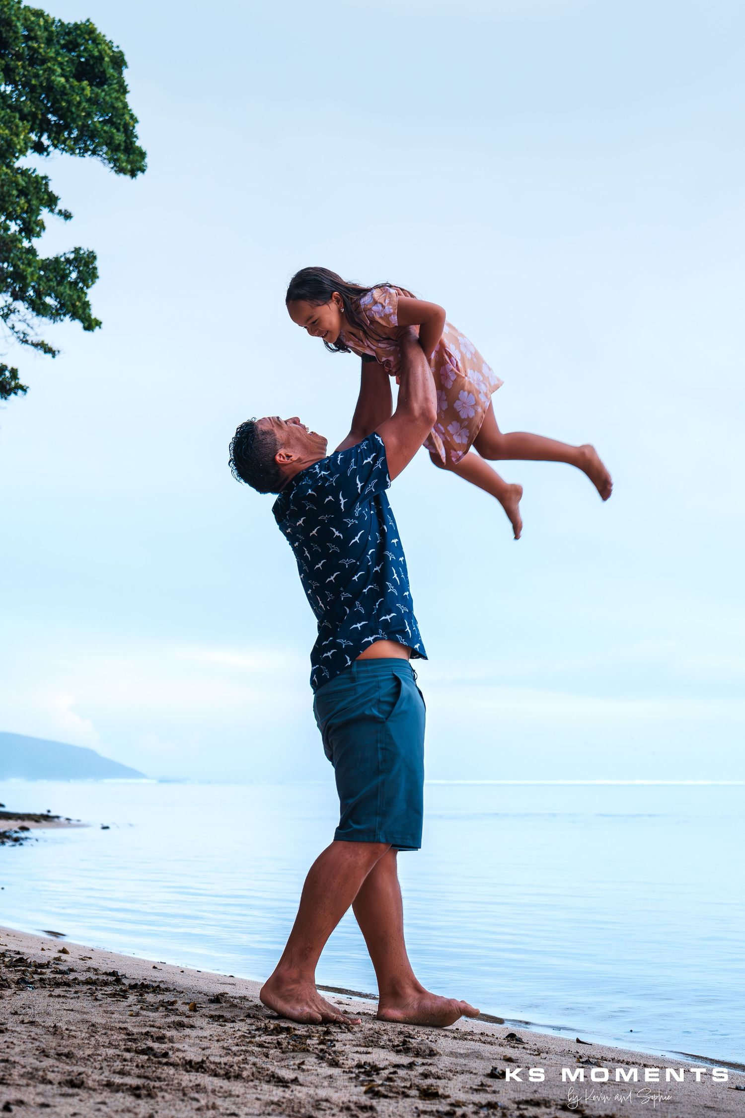 Photo d'un papa polynésien soulevant dans les airs sa fille en souriant tous les deux
