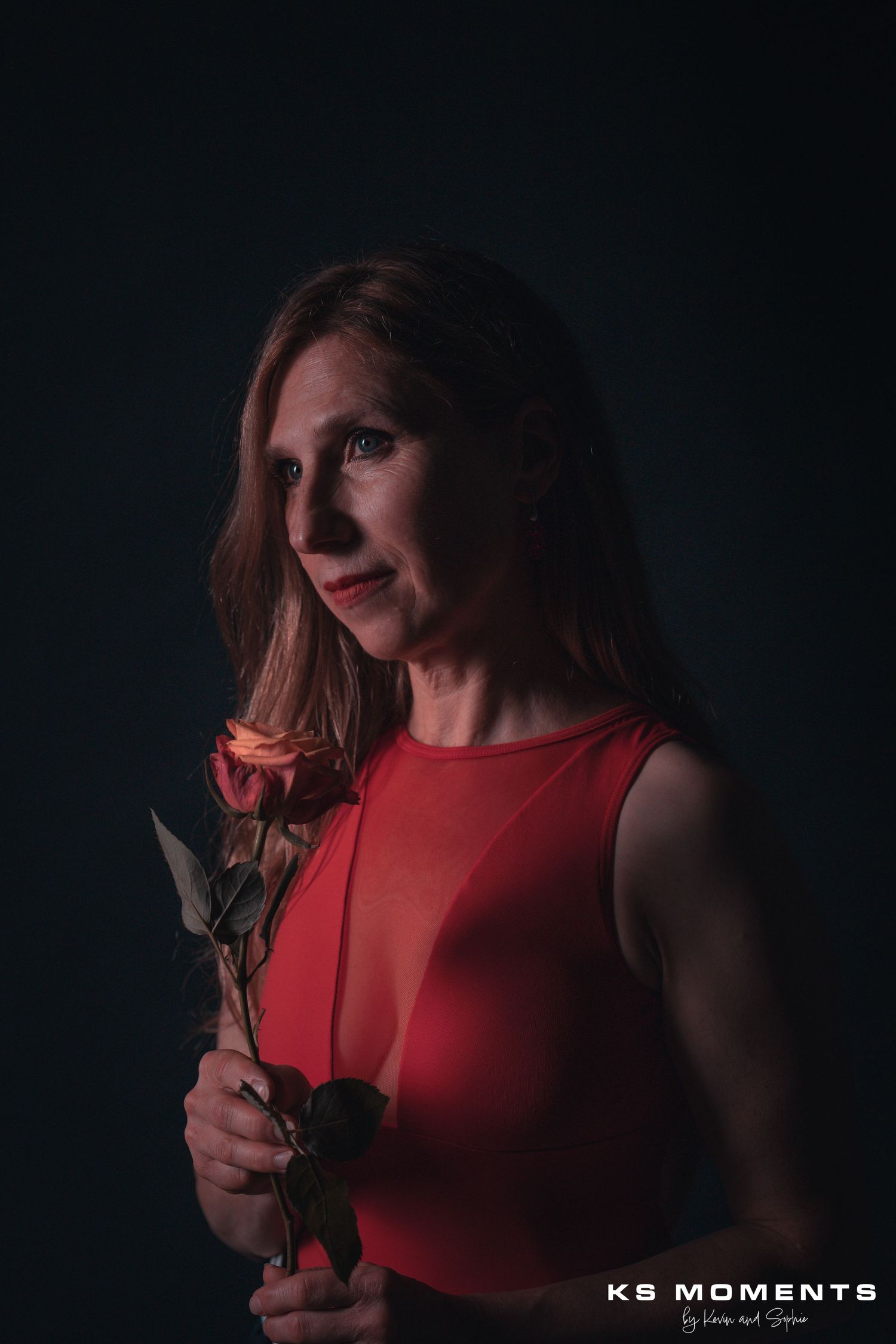 Photo d'une femme regardant vers la gauche dans un studio photo avec un fond noir et un effet clair obscur