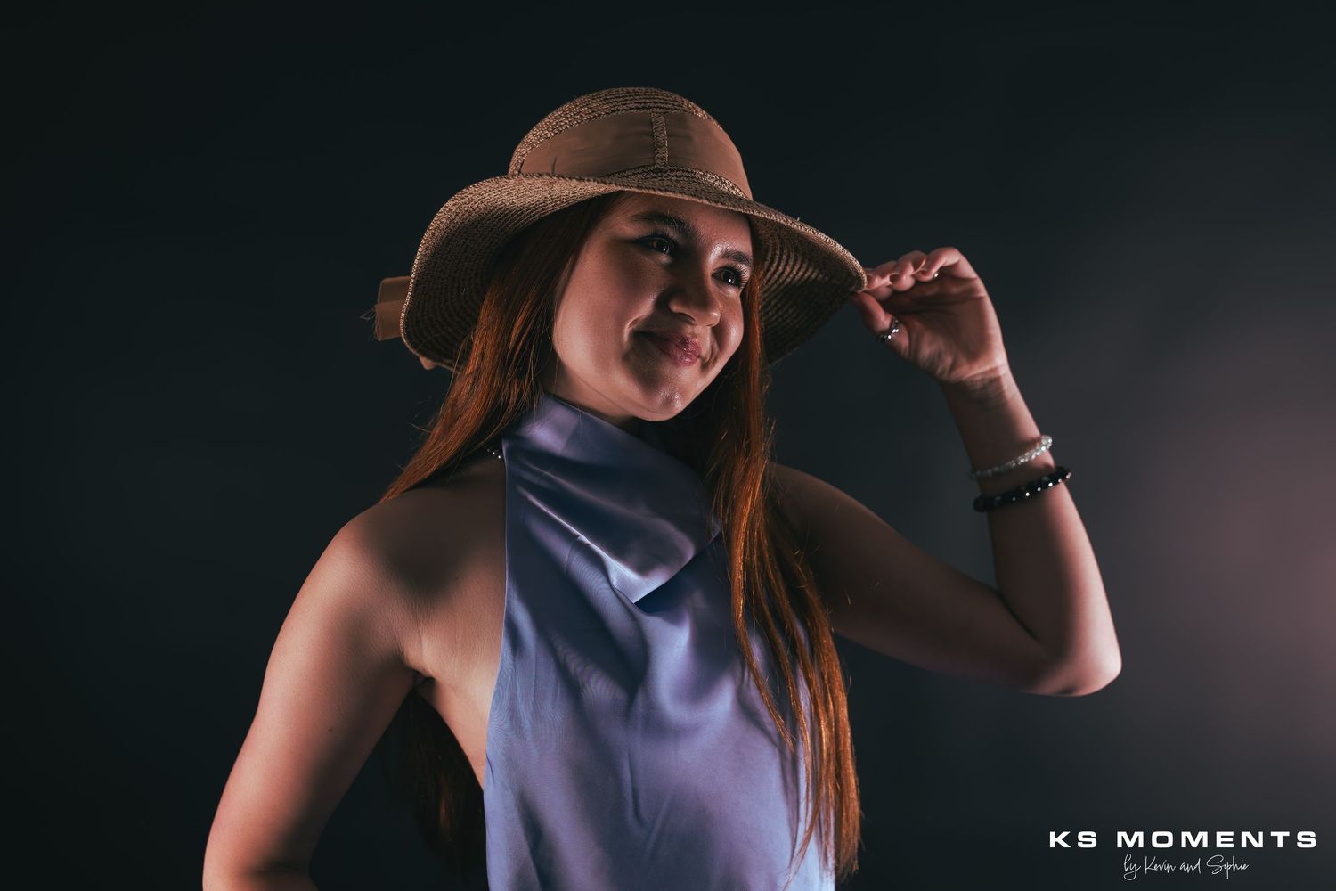 Photo d'une jeune fille souriante et regardant vers la droite dans un studio photo avec un fond noir