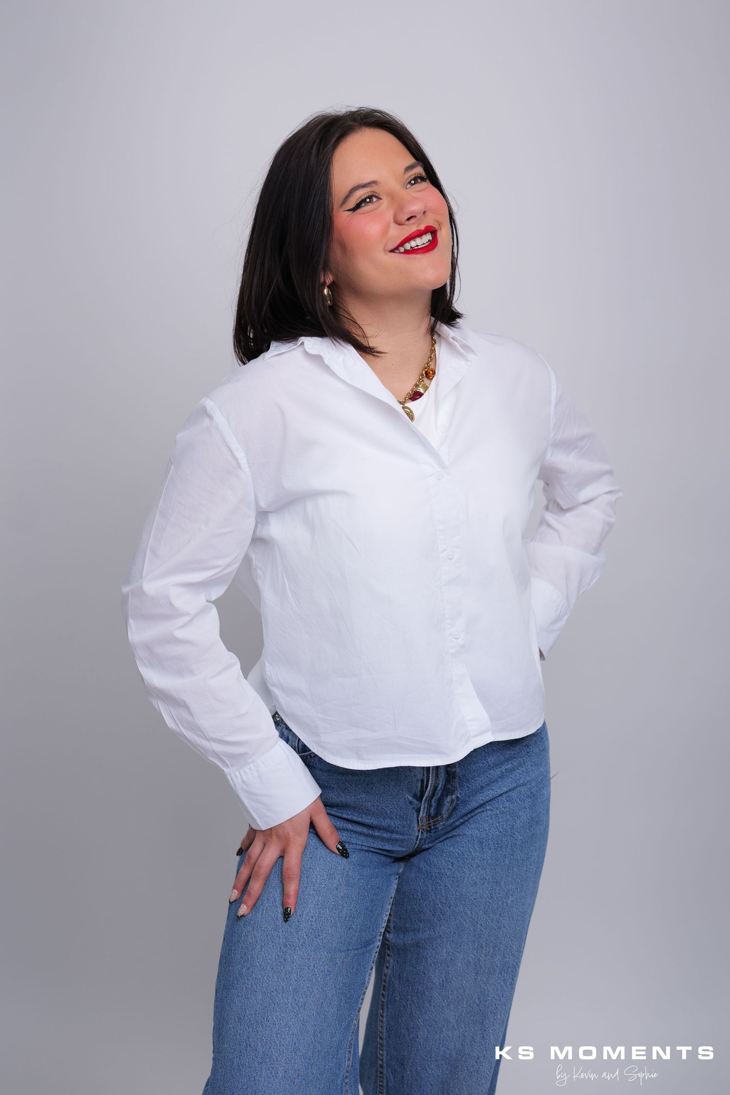 Photo d'une femme souriante debout et regardant à droite dans un studio photo avec un fond blanc