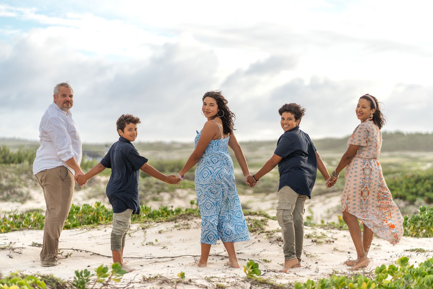 Family of five holding hands in a line on a white sandy beach in Aruba – Jonathan Geerman Studio