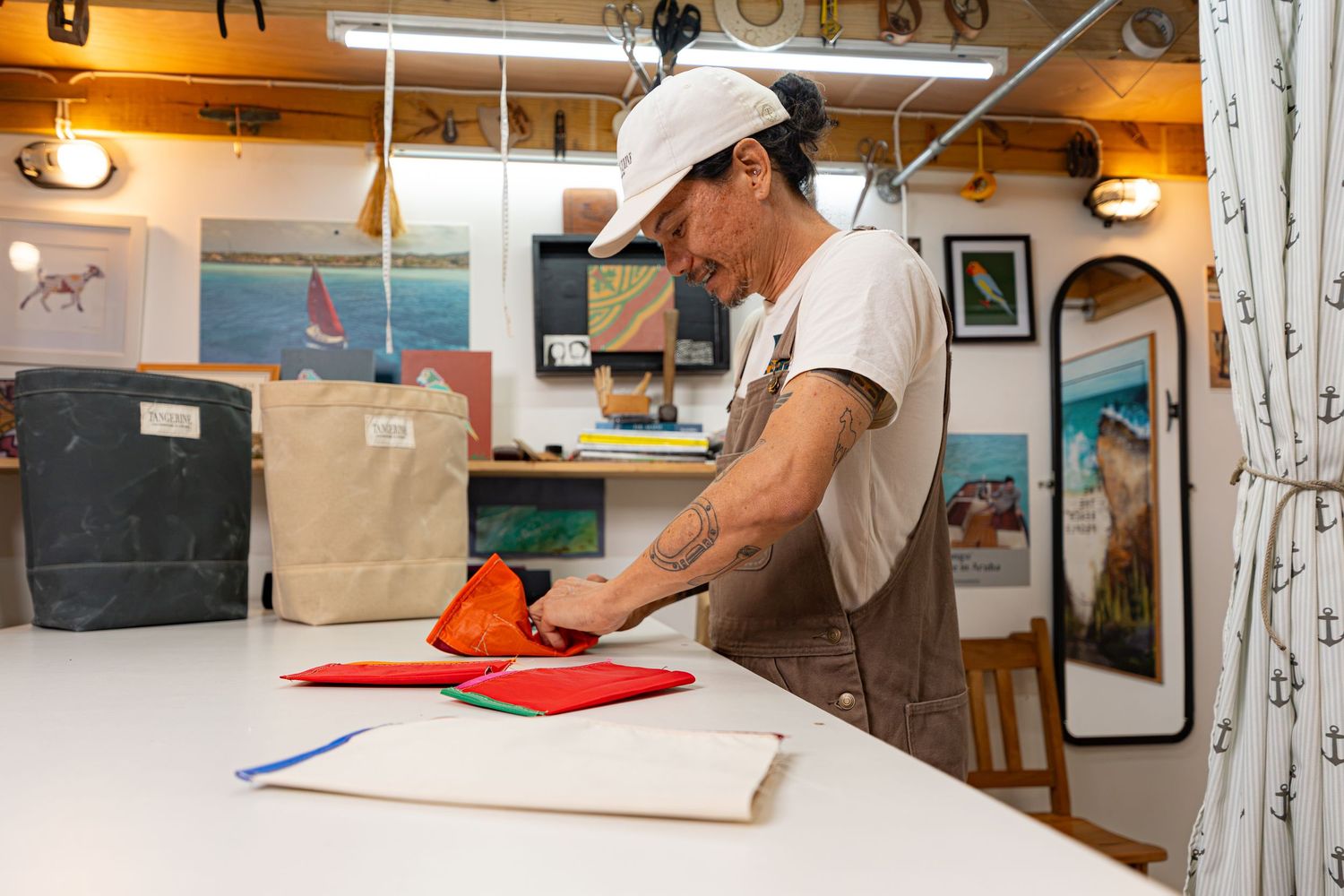Tattooed artisan arranging colorful fabric pieces on a worktable in a creative studio.