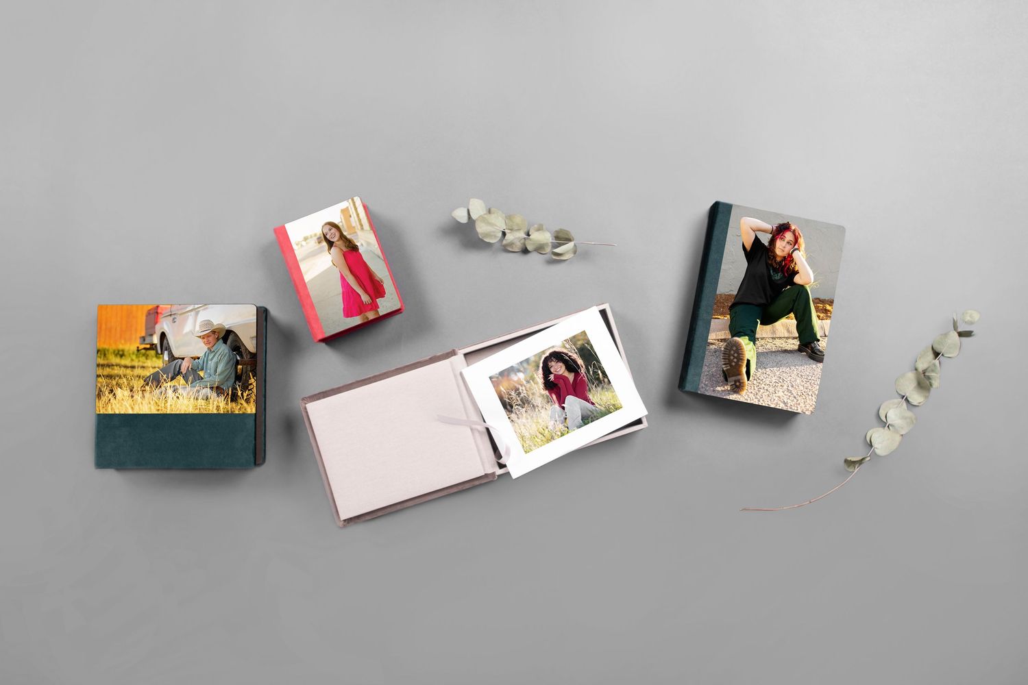 Three small hardcover photo books with senior portrait covers displayed on a gray background.  Parker Colorado Senior Portrait Products