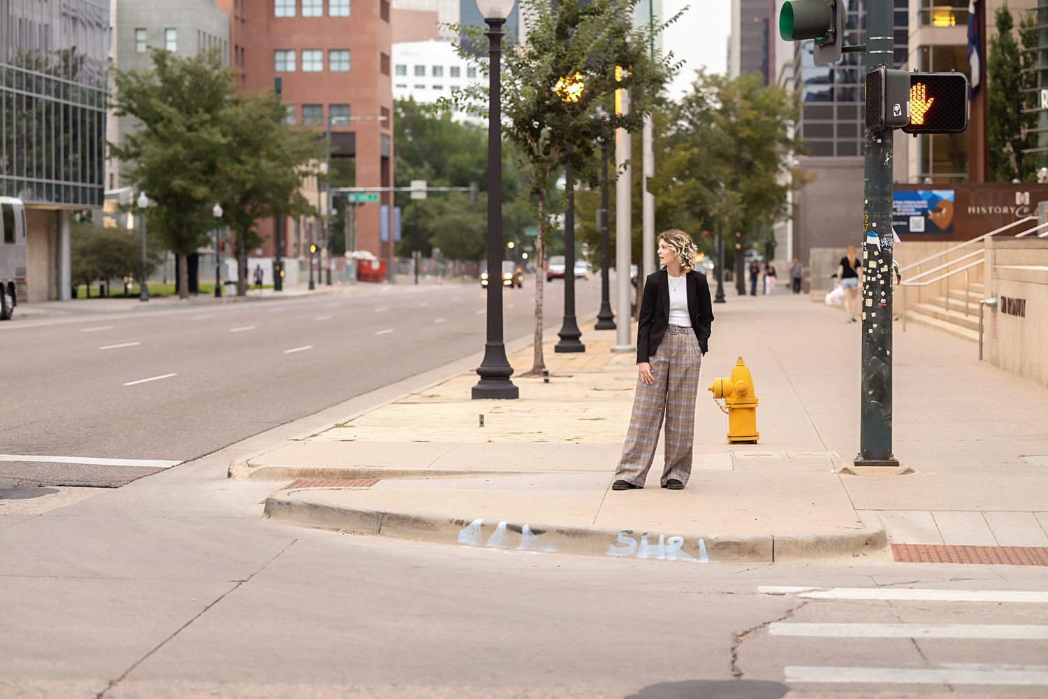Parker Colorado LGBTQ friendly images of teen in plaid wide-leg pants crossing urban street intersection with city buildings.
