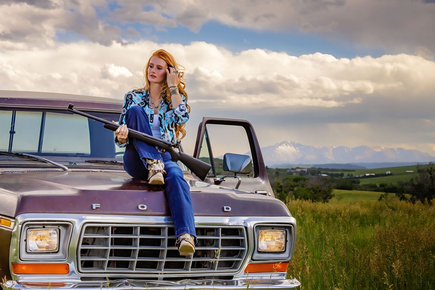 Colorado High School Blonde woman in blue denim outfit sitting on vintage Ford truck hood in rural field with dramatic cloudy sky Franktown
