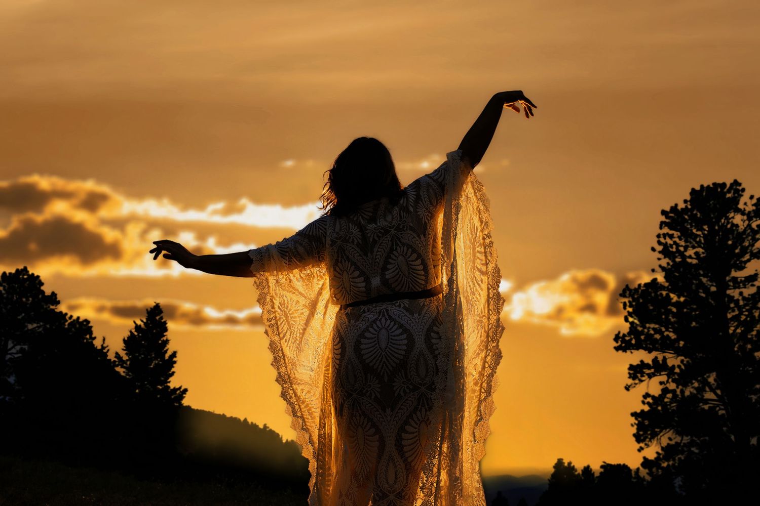 Woman in flowing lace dress silhouetted against golden sunset with arms outstretched.  Modern Branding and creative protrait Parker Colorado