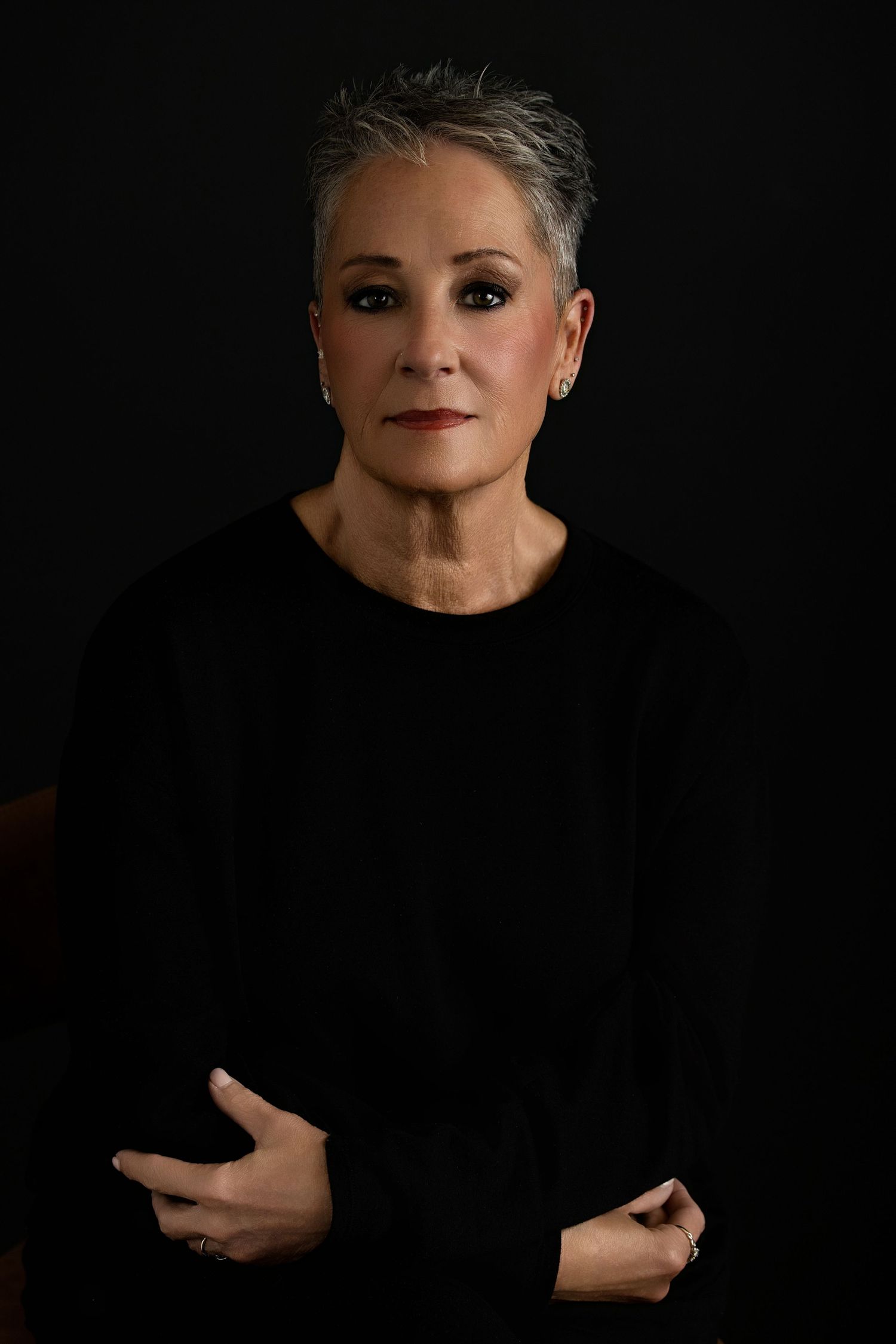A headshot  by Melissa Nansen Photography of Colorado makeup artist looking directly at camera against a dark background.