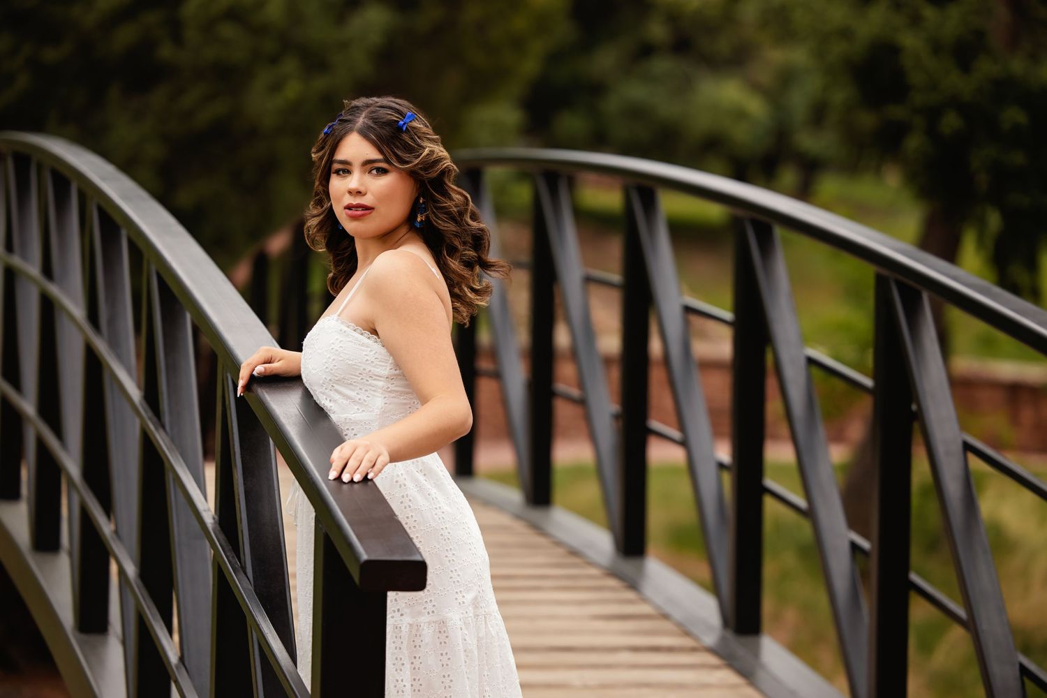 Young woman in white lace dress posing elegantly on a modern arched bridge for Lonetree Colorado Senior pictures