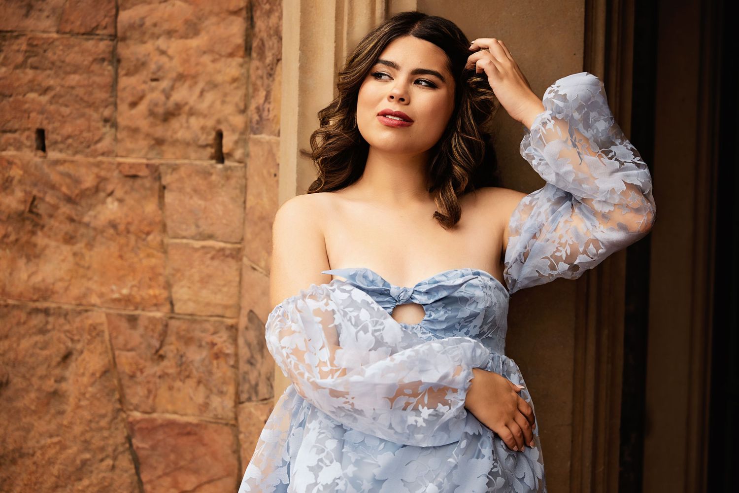 Beautiful woman in strapless blue floral lace gown posing against rustic stone wall doorway Douglas County CO High School Senior pictures
