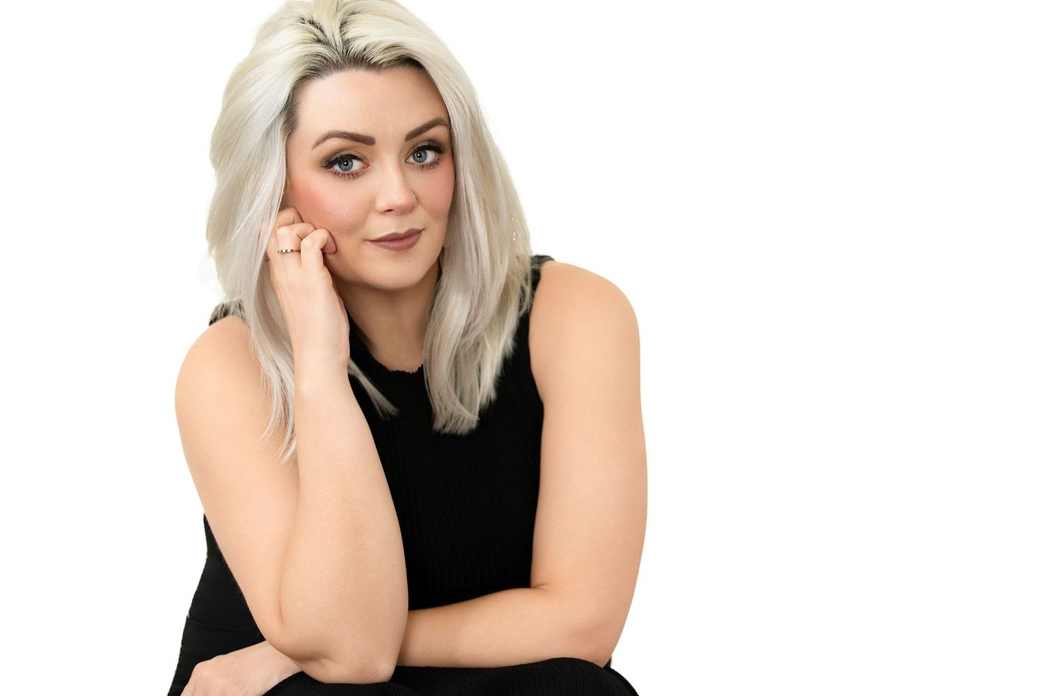 Blonde woman in black dress with hand to face in a relaxed professional studio portrait pose. Parker Colorado Headshot