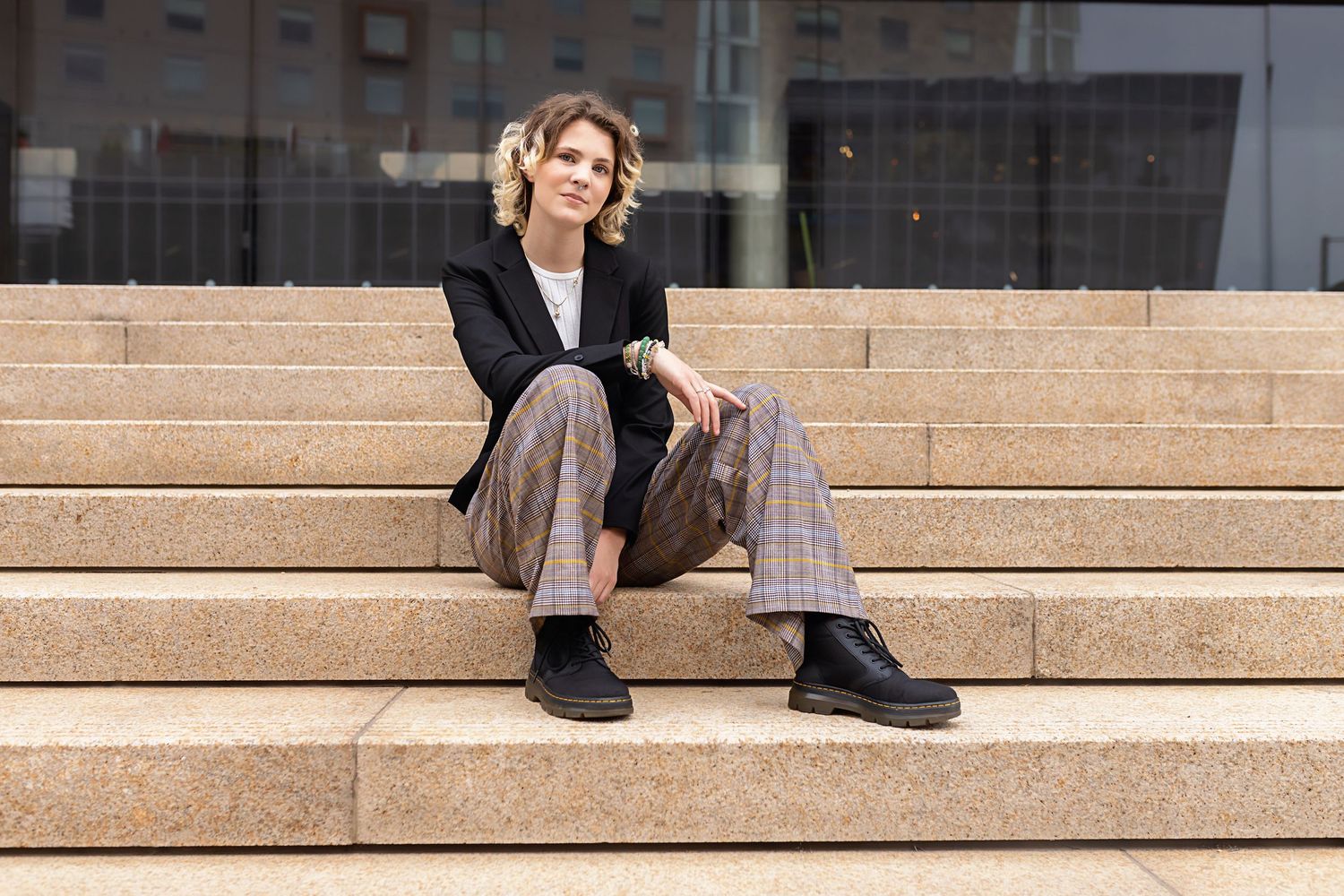 Parker Colorado LGBTQ friendly images of teen in plaid wide-leg pants and black blazer sitting on stone steps outdoors for high school photo