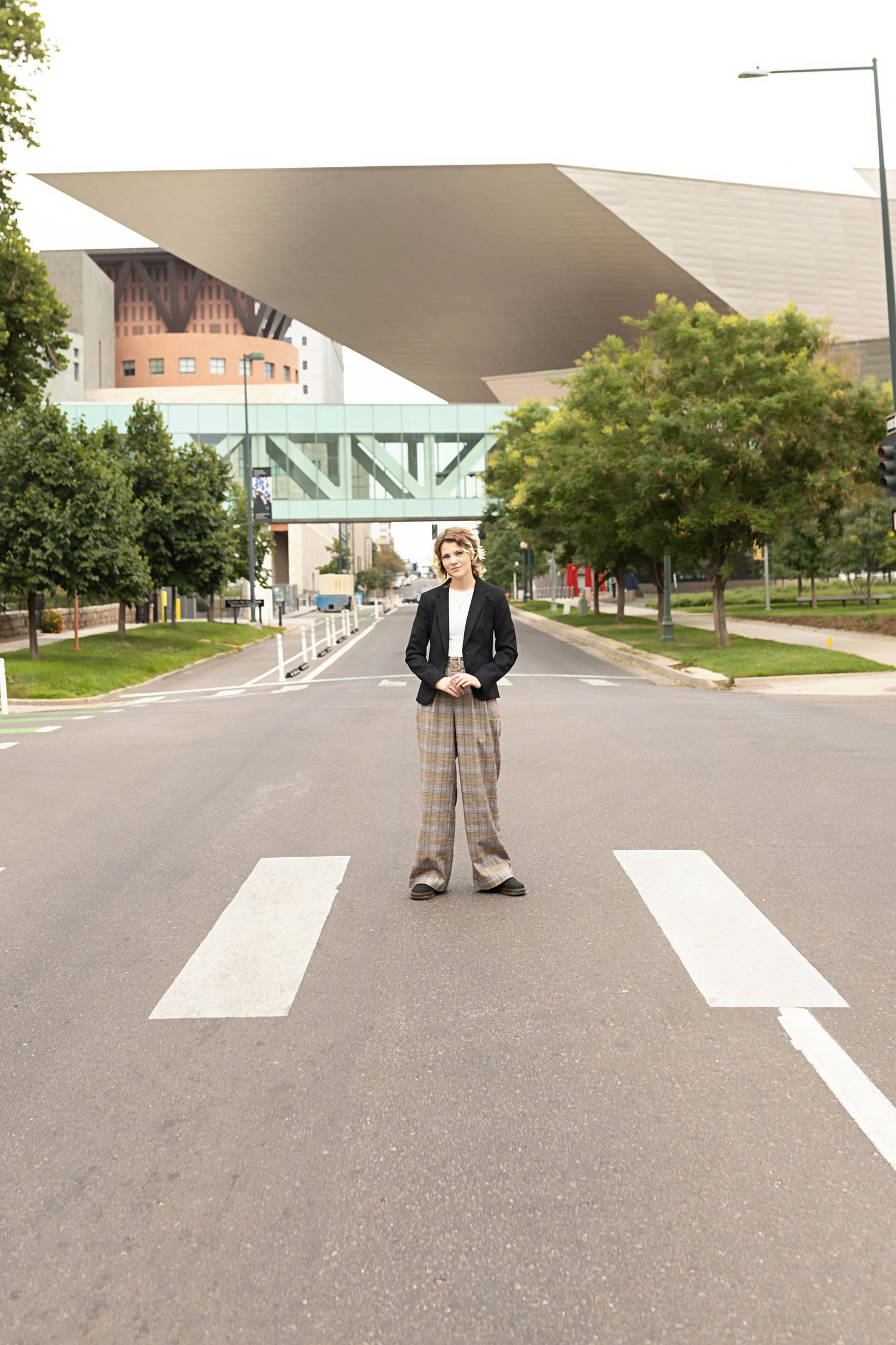 High School Senior in black blazer and plaid pants stands confidently on empty urban crosswalk street Denver Photoshoot