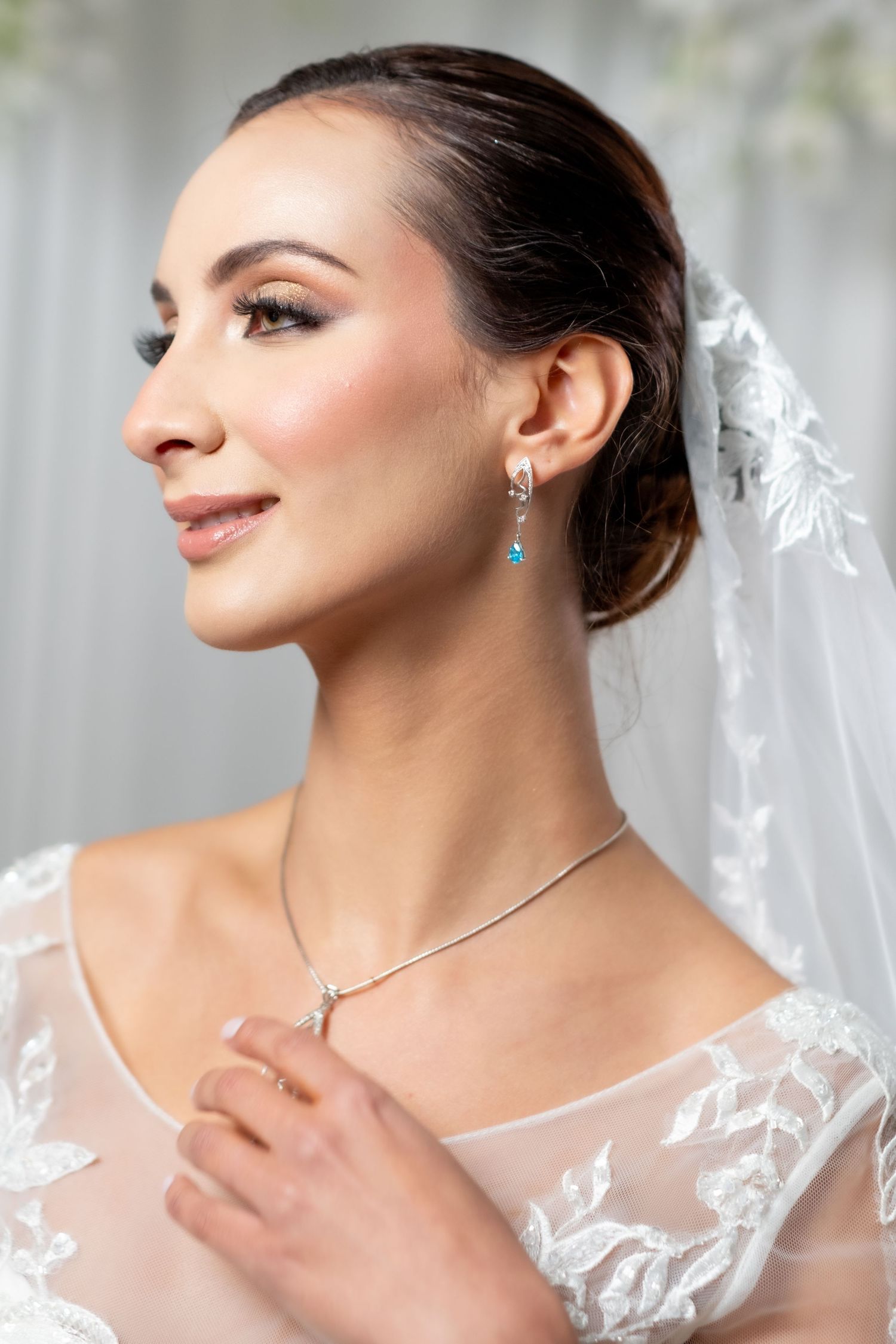 Beautiful bride in lace veil showcasing blue topaz drop earrings and necklace.