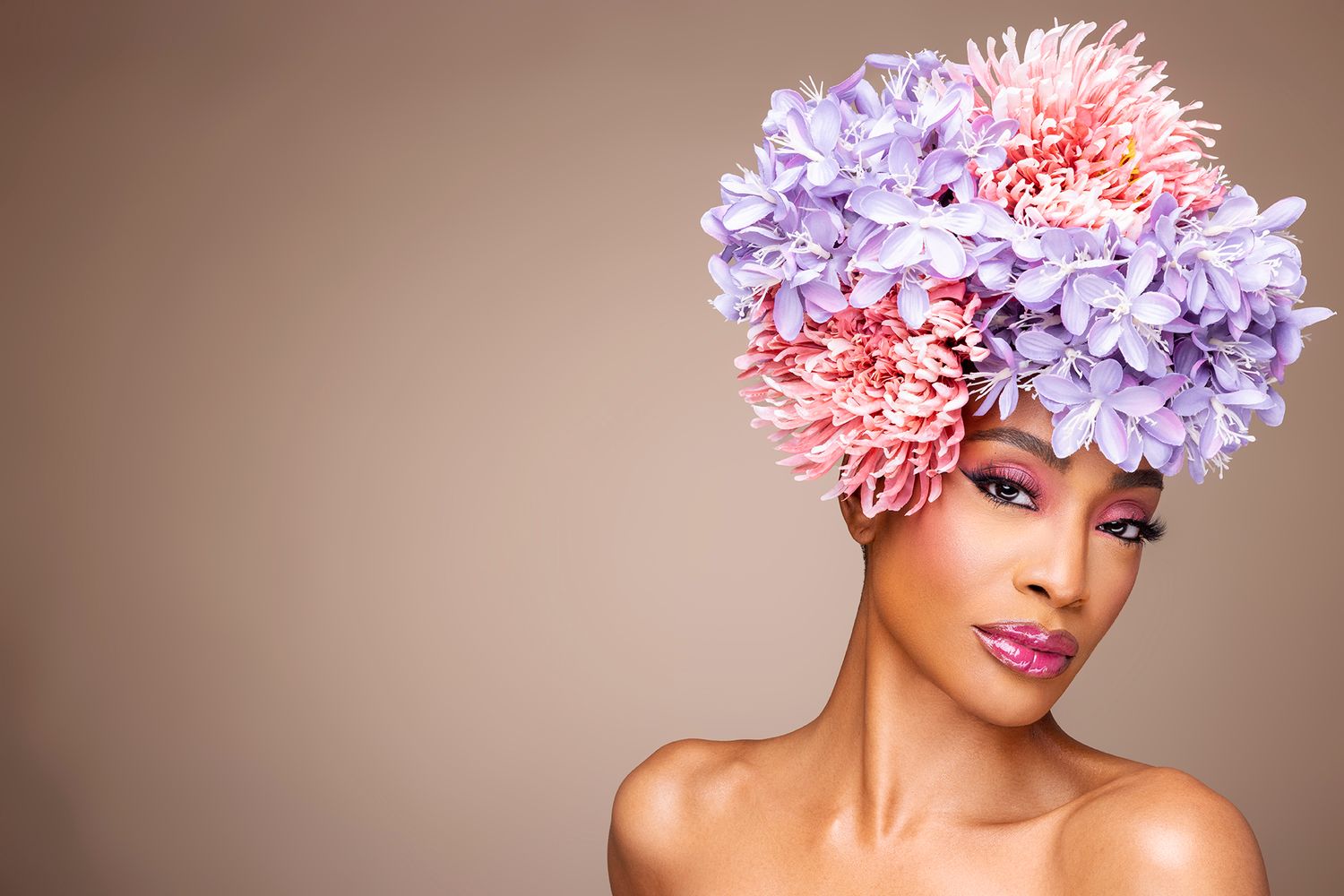 Fashion portrait showcasing vibrant pink and purple floral headpiece against neutral background.