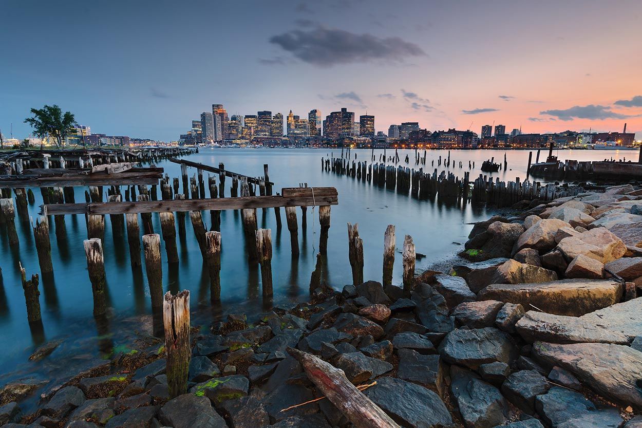 View of Boston from Boston Logan airport side of the harbor with derelict pier in foreground images taken at dusk