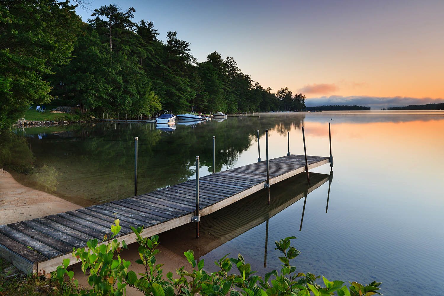 Color landscape photograph showing dock leading into lake in New Hampshire's White Mountain region at sunrise by architectural photographer