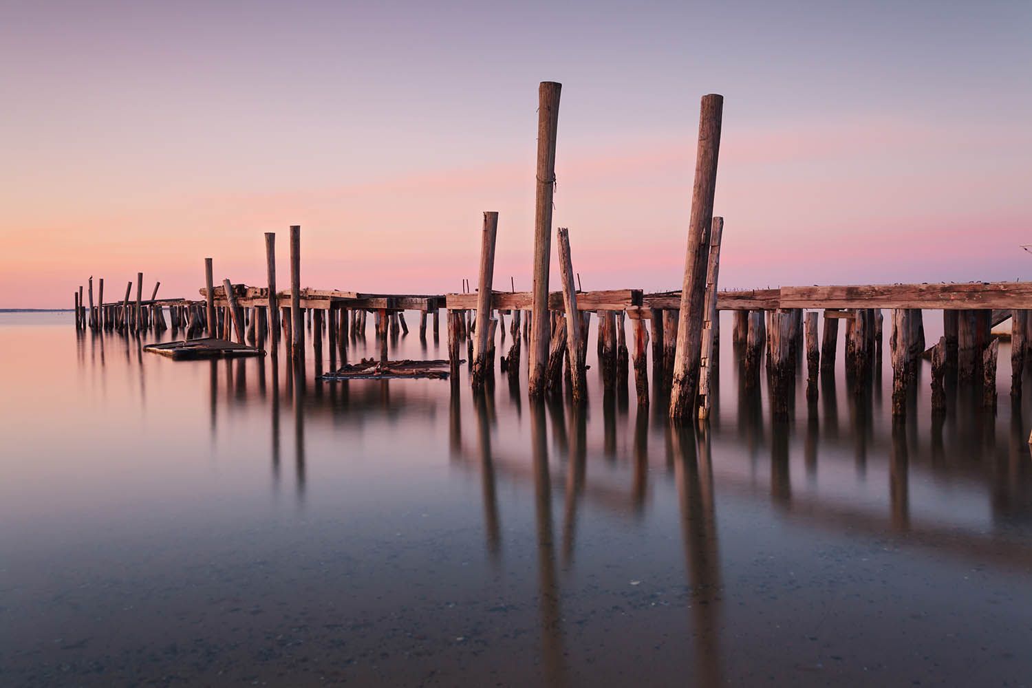 Color landscape photograph showing old dock falling into the sea at Cape Cod