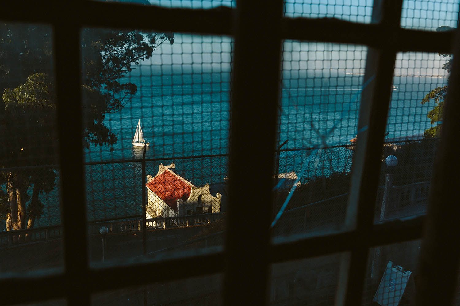 Color landscape photograph taken from Alcatraz in San Francisco showing view through broken glass window.