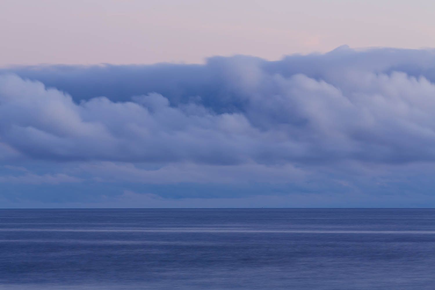 Color landscape photograph of Terceira Island in the Azores Portugal, showing the view out to sea taken at dusk with very moody clouds